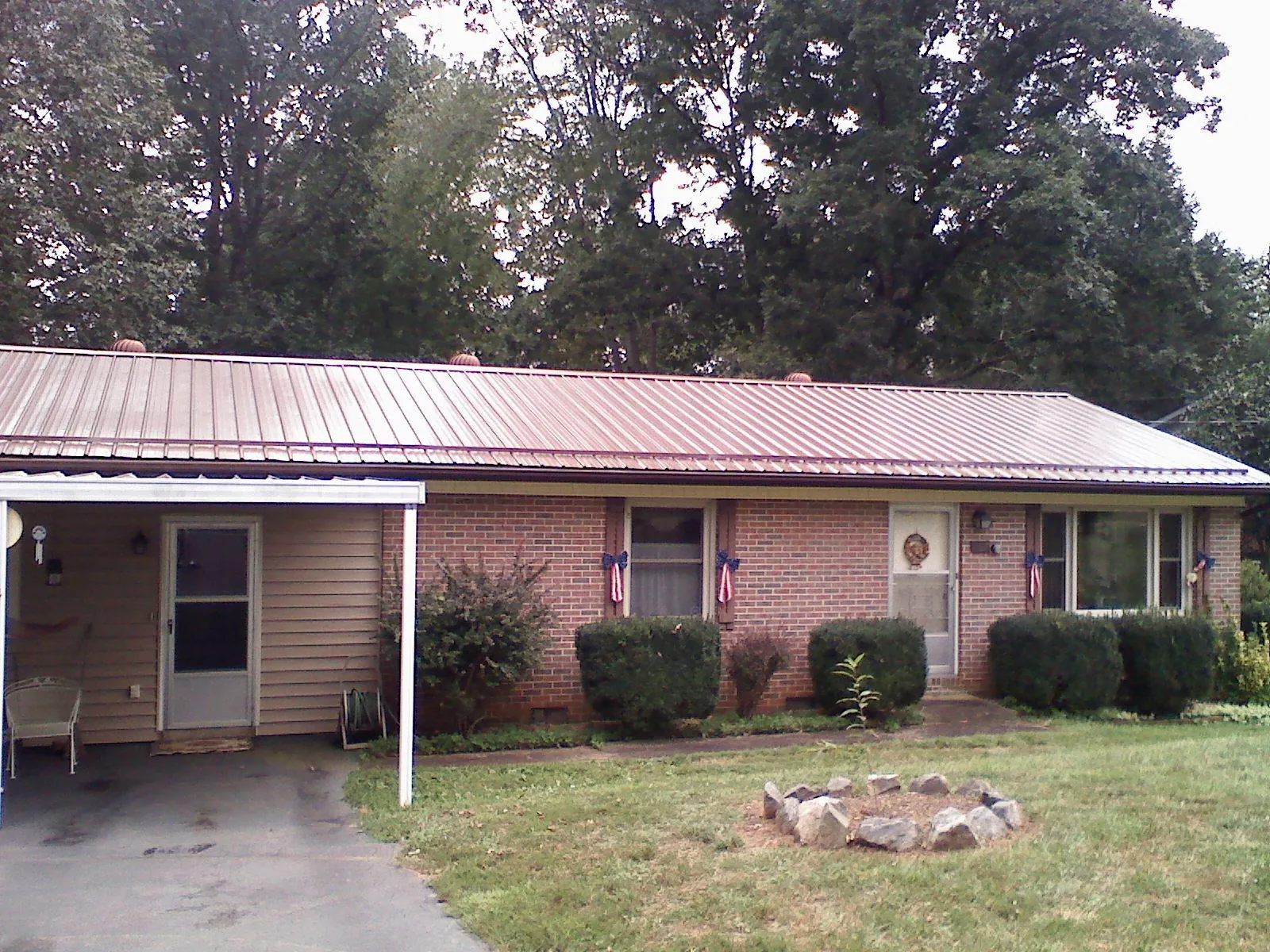 Bronze metal roof and carport on a brick ranch home — Roof Repair work by our crew in Dansville
